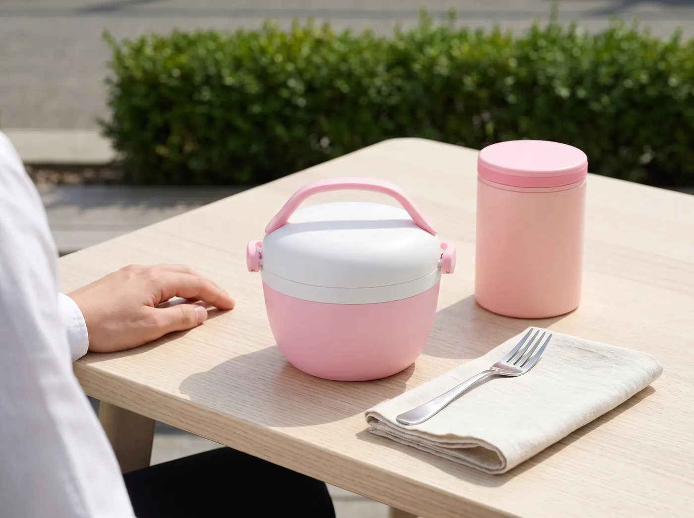 Rosa Thermobrotdose und Lebensmittelthermoskanne Runbott auf einem Terrassentisch